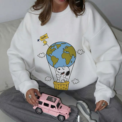 Person wearing a white sweatshirt with a cartoon design of Snoopy and the world, holding a pink toy car.
