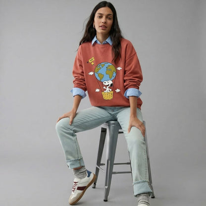 Person wearing a red sweater with a graphic design, sitting on a stool against a gray background