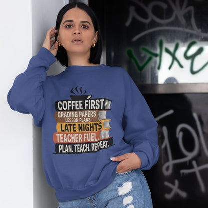 Person wearing a blue sweatshirt with a humorous teacher design, standing against a graffiti-covered wall.