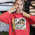 Person wearing a red sweatshirt with a graphic design and text, pointing to the design.