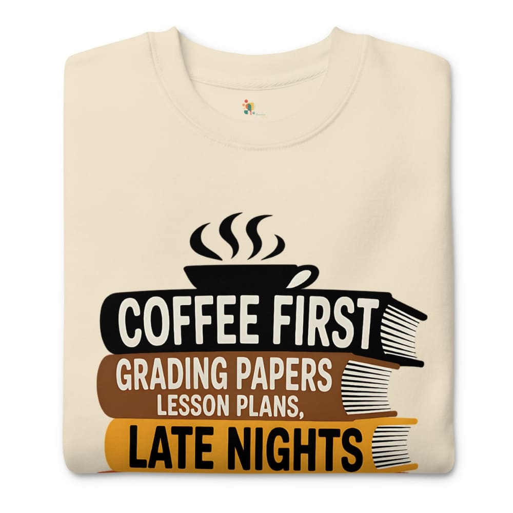 Beige t-shirt with a graphic design featuring a coffee cup and books, text 'Coffee First, Grading Papers, Lesson Plans, Late Nights'.