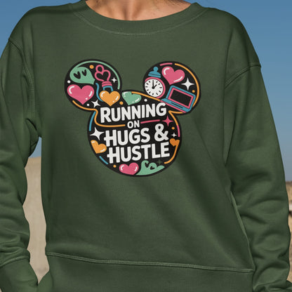 Green sweatshirt with colorful design and text 'Running on Hugs & Hustle' on a blue sky background