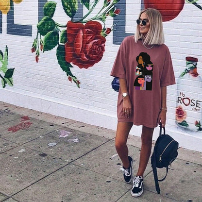 Person wearing a pink oversized t-shirt with a graphic design, standing in front of a mural.