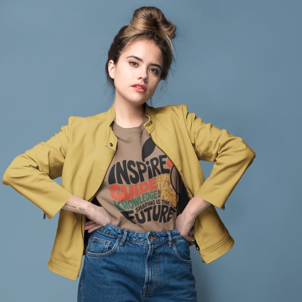 Woman wearing a mustard jacket, graphic t-shirt, and blue jeans against a blue background