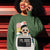 Person wearing a green sweatshirt with a cartoon character design, standing against a red and black background.