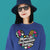 Person wearing a blue sweatshirt with colorful design and text on a teal background