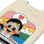 Beige t-shirt with a colorful cartoon character design on a white background