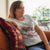 Woman wearing a t-shirt with a graphic design sitting on a couch.
