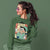 Woman wearing a green sweatshirt with a cartoon character design on a green background