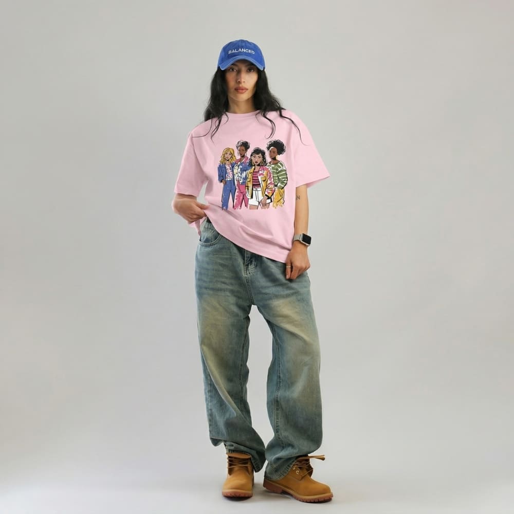 Person wearing a blossom-pink t-shirt with a graphic design, blue jeans, and a blue cap on a plain background