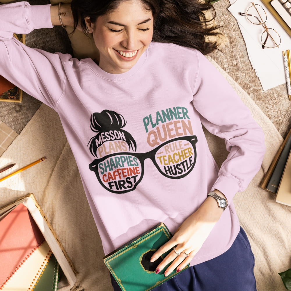 Woman wearing a pink sweatshirt with text and graphics, surrounded by stationery items.