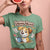 Person wearing a green t-shirt with a cartoon dog graphic and text on a pink background