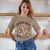 Woman wearing a t-shirt with a graphic design and text, standing indoors.