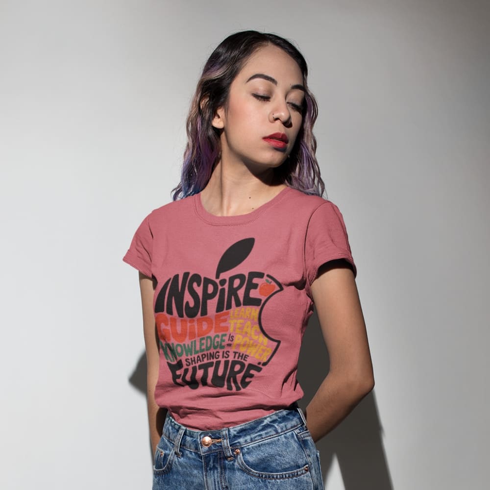 Woman wearing a pink t-shirt with text and graphics, standing against a plain background