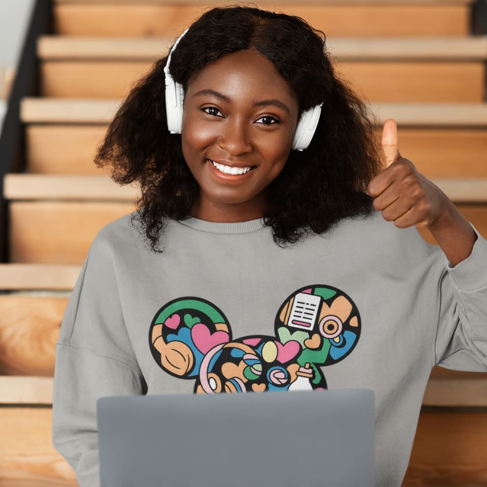 Woman wearing headphones and a sweatshirt with colorful designs, sitting on stairs.