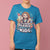 Person wearing a blue t-shirt with a colorful graphic and text on a pink background