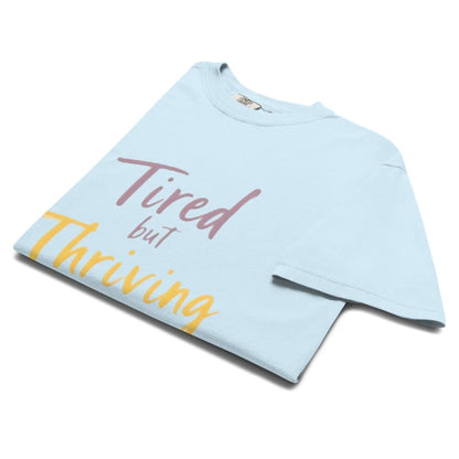 Garment-dyed relaxed fit t-shirt with motivational quote “Tired But Thriving” in modern handwritten script