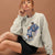 Woman wearing a gray sweatshirt with a graphic design on a brown background