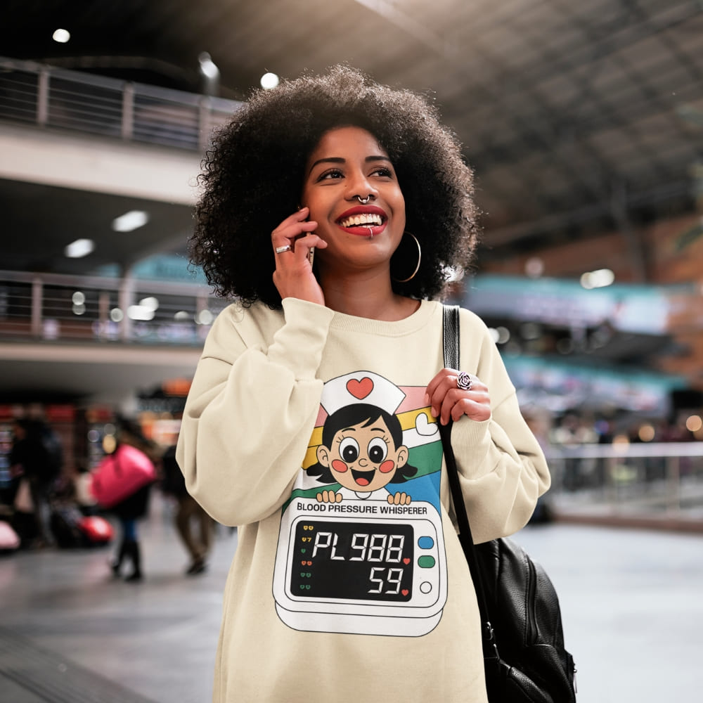 Woman wearing a cream-colored sweatshirt with a cartoon character design, standing in an indoor setting.