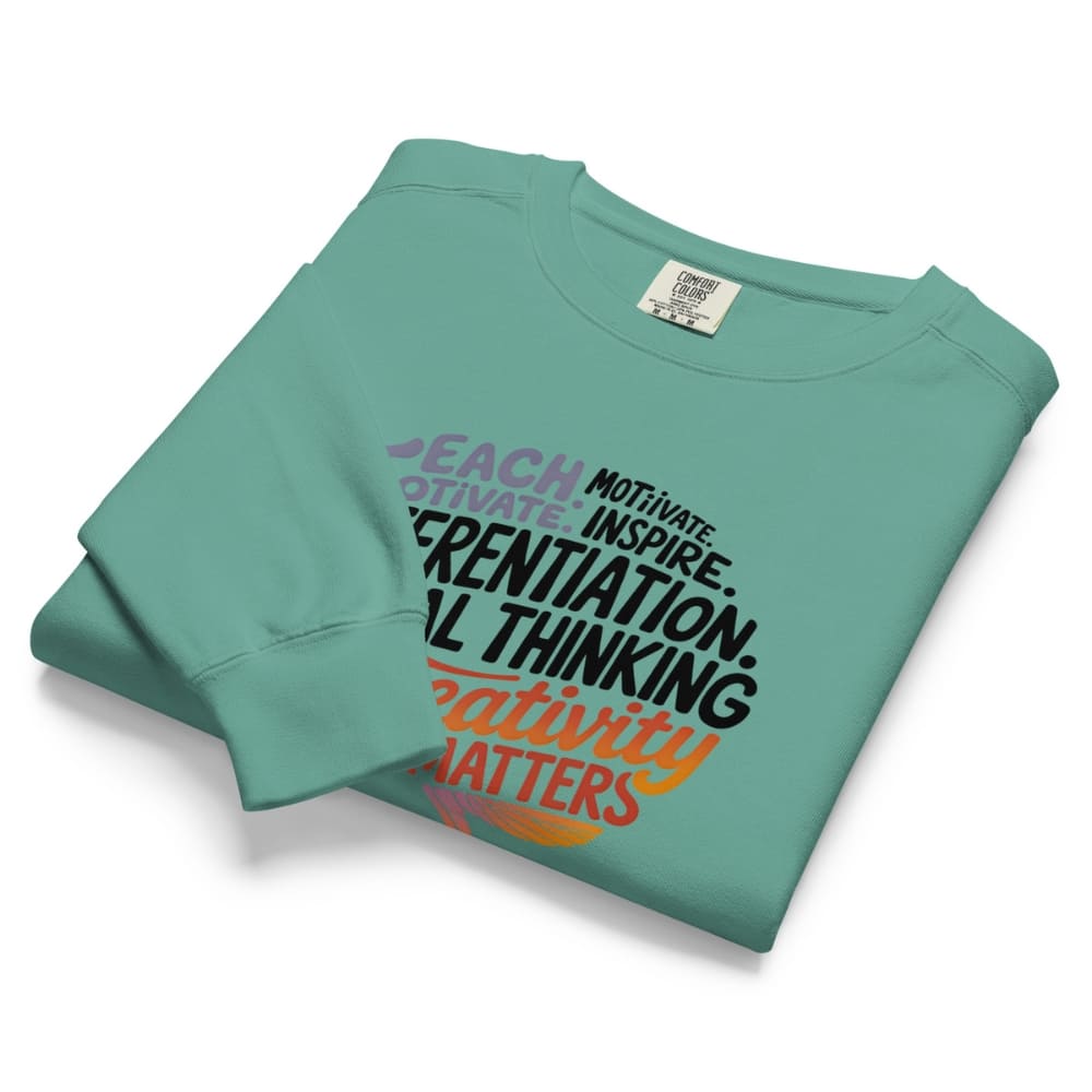 Folded teal sweatshirt with motivational text on a white background