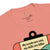 Pink t-shirt with a graphic and text 'My scrubs are cute, my skills are killer' on a white background.