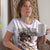 Person wearing a white t-shirt with a graphic design and text, holding a mug.
