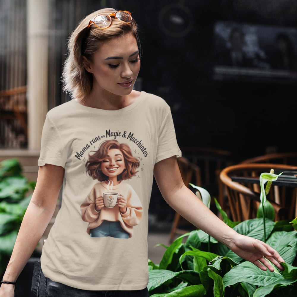 Woman wearing a t-shirt with a graphic design of a woman holding a coffee cup, set against a blurred outdoor background.