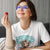Woman wearing a white t-shirt with a graphic design, holding a red object.