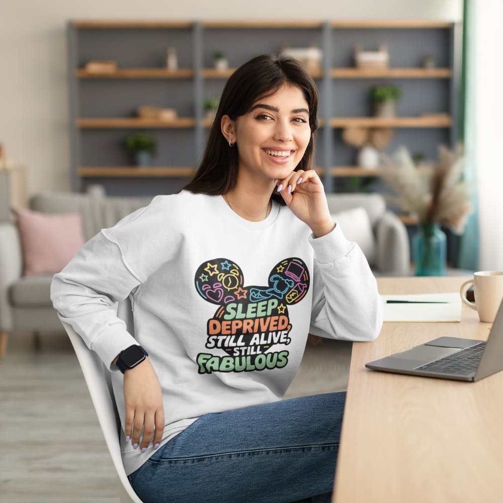 Woman wearing a sweatshirt with a colorful design and text, sitting at a desk in a modern office setting.