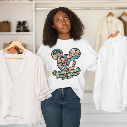 Woman wearing a white t-shirt with a colorful graphic and text, standing in a room with clothes on hangers.