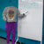 Person wearing a sweatshirt with a humorous quote, standing next to a whiteboard with 'Welcome' written on it.
