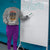 Person wearing a sweatshirt with a humorous quote, standing next to a whiteboard with 'Welcome' written on it.