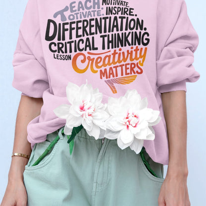 Person wearing a pink sweatshirt with educational text and holding flowers against a light blue background