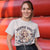 Person wearing a t-shirt with a graphic and text in front of red cylindrical objects