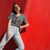 Woman wearing a gray t-shirt with a graphic design against a red background