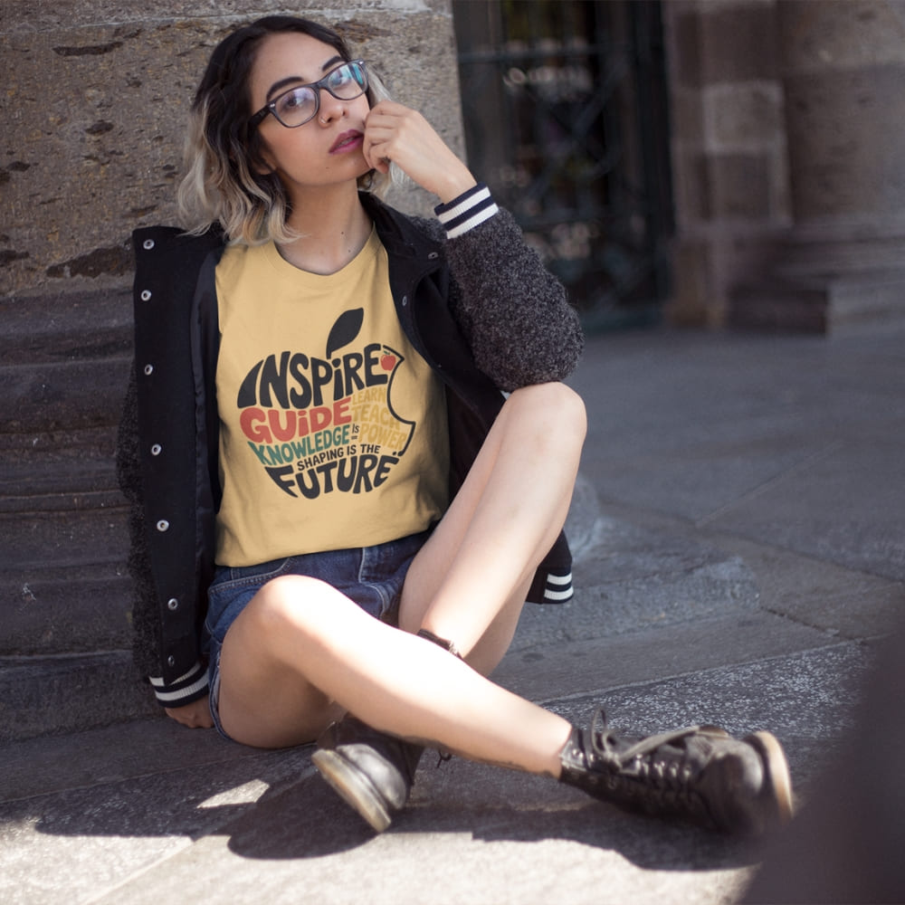 Person wearing a yellow t-shirt with text sitting on steps outdoors
