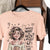 Peach t-shirt with a graphic of a woman and text on a hanger.