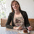 Woman wearing a t-shirt with a graphic design, sitting at a table with a plate of food.