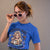 Woman wearing a blue t-shirt with a graphic design and sunglasses, against a plain background