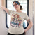 Person wearing a t-shirt with a graphic design and text, standing indoors.