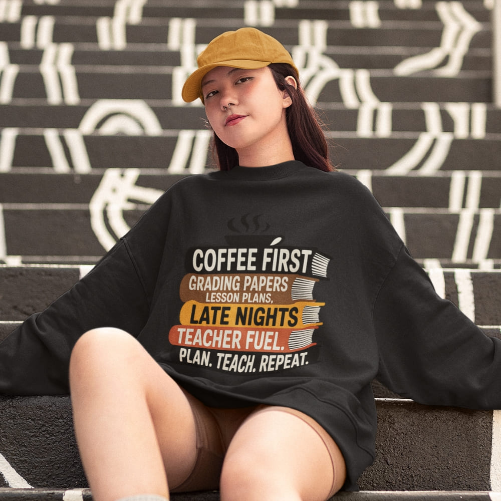 Person wearing a black sweatshirt with a humorous teacher quote, sitting on stairs.