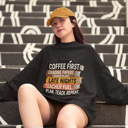 Person wearing a black sweatshirt with a humorous teacher quote, sitting on stairs.