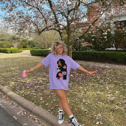 Person wearing a purple t-shirt with a graphic design outdoors under cherry blossom trees.