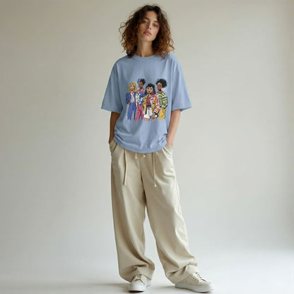 Person wearing a denim-blue t-shirt with a graphic design, beige pants, and white sneakers on a plain background