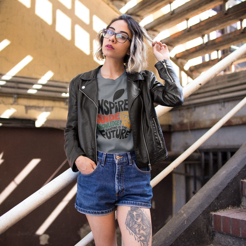 Woman wearing a graphic t-shirt, leather jacket, and denim shorts in an industrial setting