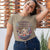 Woman wearing a t-shirt with a graphic design and text, standing against a wooden panel background.