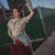 Woman wearing a t-shirt with a graphic design and text, standing outdoors.