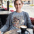 Woman wearing a shirt with a graphic design sitting at a table with a coffee cup.