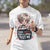 Person wearing a white t-shirt with a graphic design and text outdoors.
