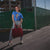 Person wearing a blue t-shirt and holding a red bag in an urban setting